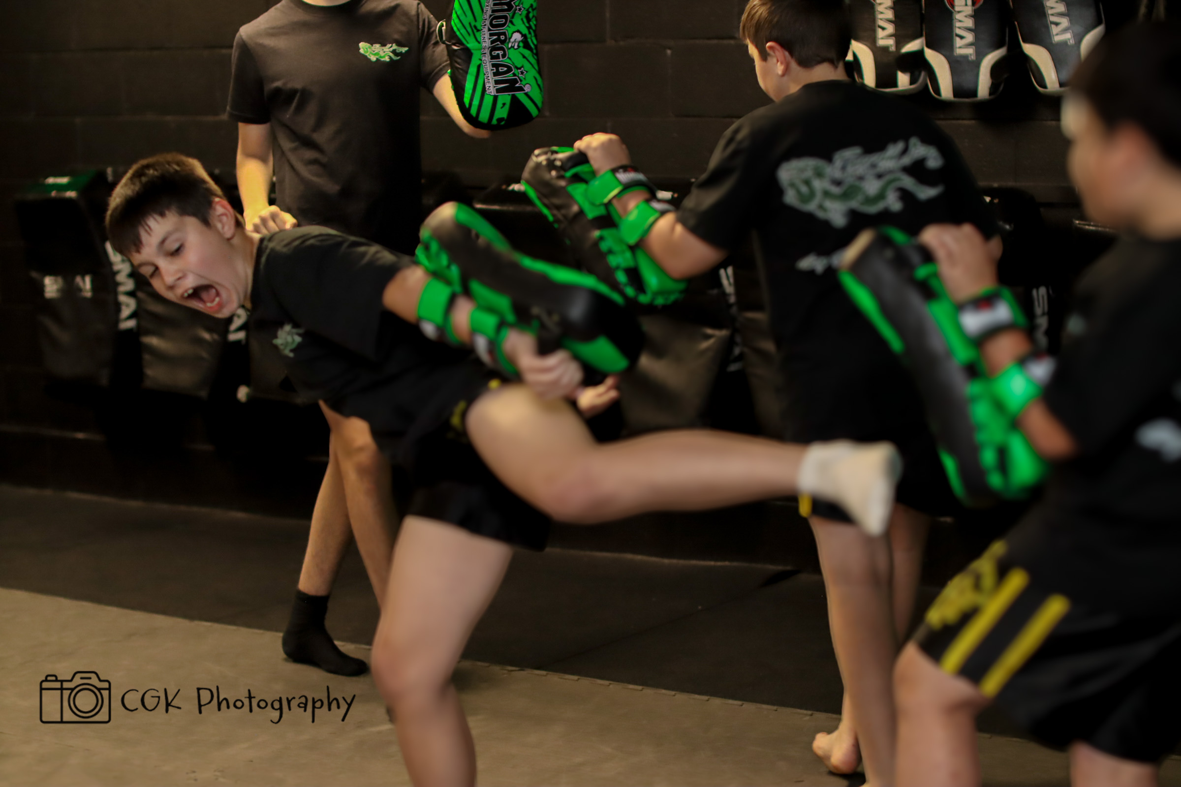 Kids practicing MMA techniques with protective gear in a safe, supervised environment at Emerald Dragon Martial Arts.